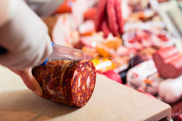 Butcher woman cutting chorizo sausage Stock photo © Kzenon