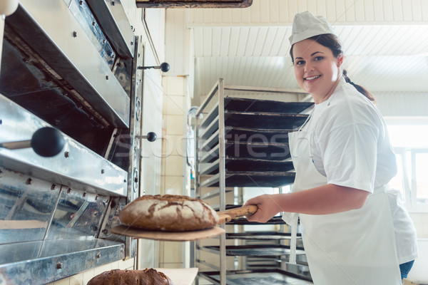 Baker getting fresh bread with shovel out of oven Stock photo © Kzenon