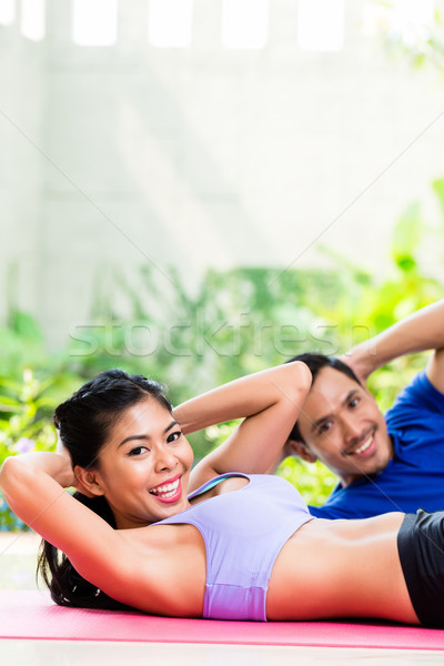 Asian fitness couple doing sit-up in tropical home Stock photo © Kzenon