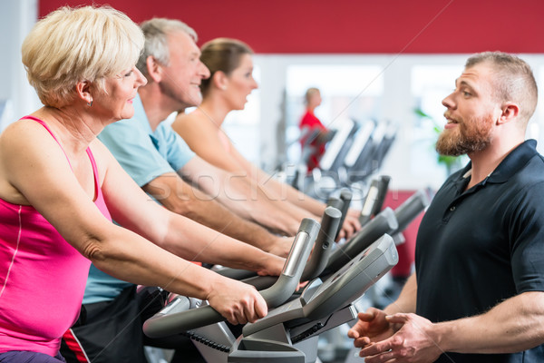 Stock photo: Personal trainer instructs senior woman about spinning at the gy