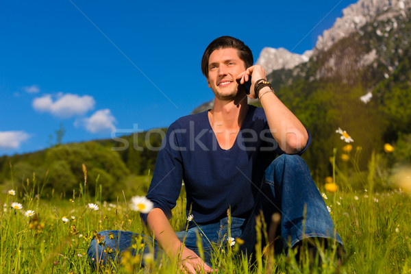 man with phone  sitting in the mountains  Stock photo © Kzenon
