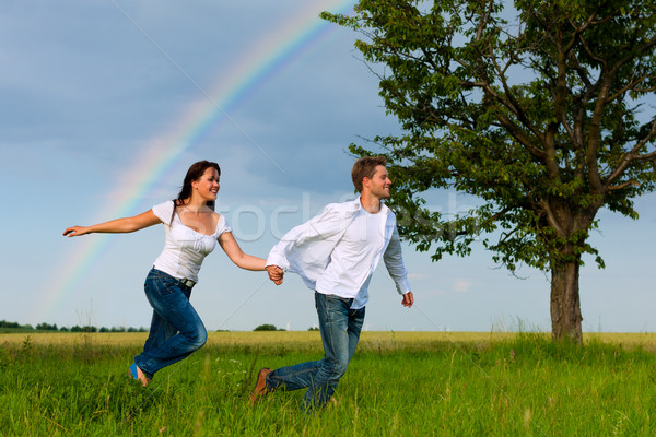 Happy couple running on a meadow Stock photo © Kzenon