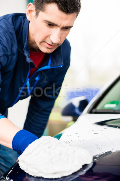 Hard-working man polishing car with white microfiber mitt Stock photo © Kzenon