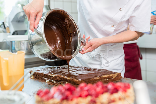 Confectioner putting chocolate as frosting on cake Stock photo © Kzenon