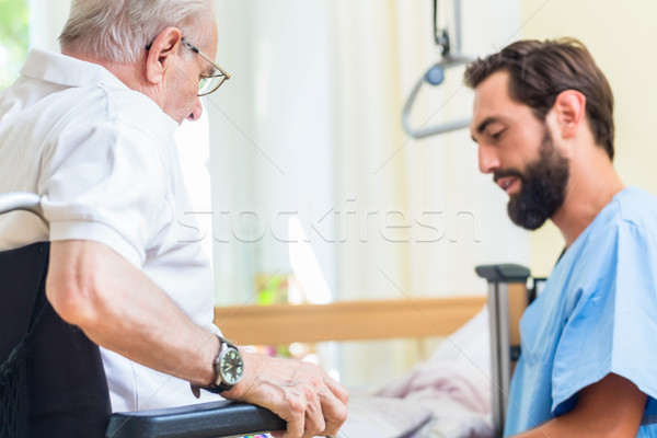 Elderly care nurse helping senior from bed to wheel chair  Stock photo © Kzenon