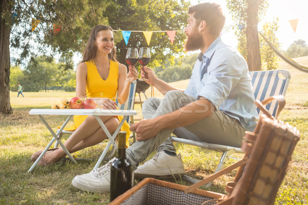 Beautiful couple in love toasting with red wine during romantic picnic Stock photo © Kzenon