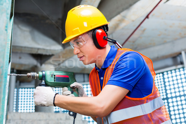 Asian worker drilling in construction site wall Stock photo © Kzenon