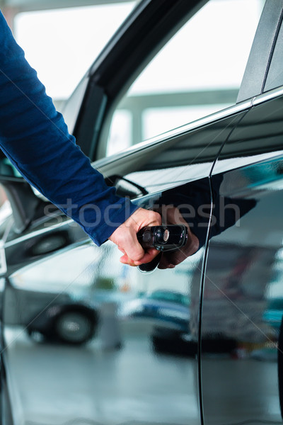 Young man with auto in car dealership Stock photo © Kzenon