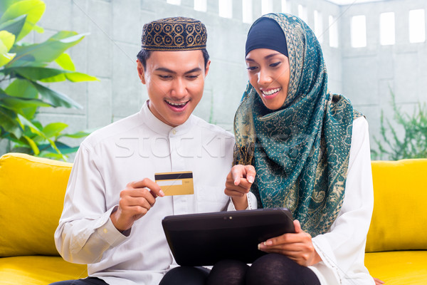 Asian Muslim couple shopping online on pad in living room Stock photo © Kzenon