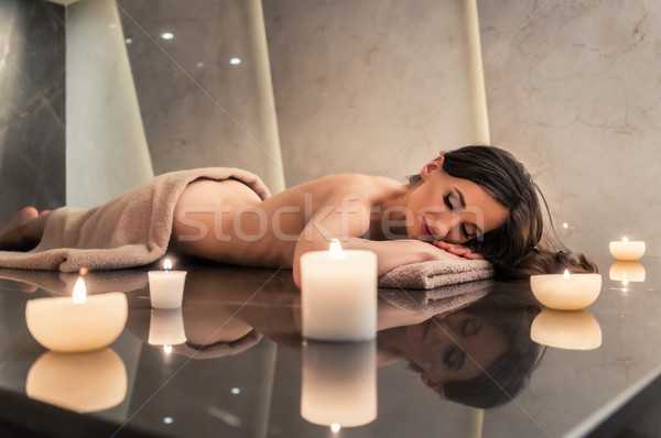 Scented candle next to young woman on marble massage table at sp Stock photo © Kzenon