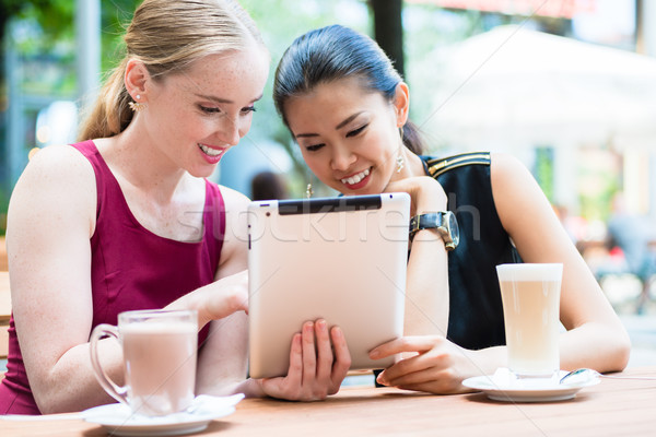 Two young female best friends using a tablet PC outdoors at a tr Stock photo © Kzenon