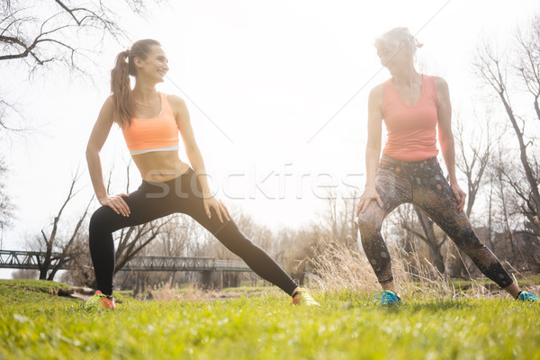 Mother and daughter stretching on meadow doing gymnastics Stock photo © Kzenon