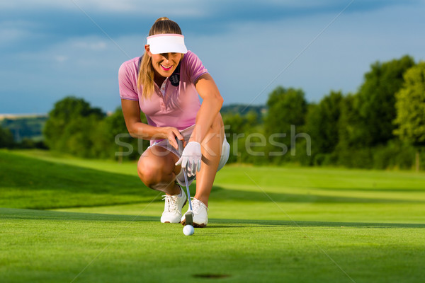 Young female golf player on course aiming for her put Stock photo © Kzenon