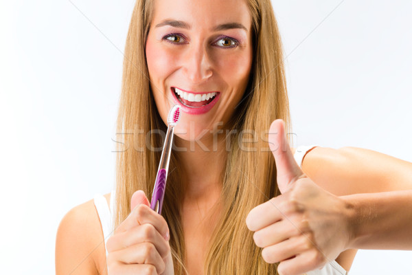 Woman brushing her teeth with a toothbrush Stock photo © Kzenon