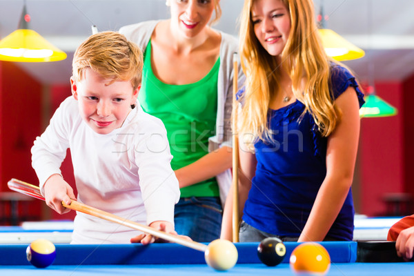 Boy playing pool billiard with family Stock photo © Kzenon