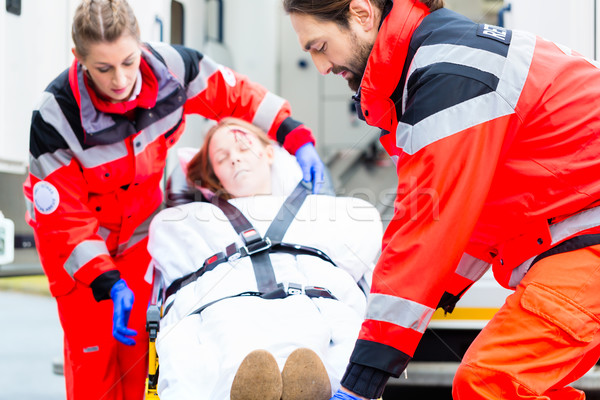 Stock photo: Ambulance helping injured woman on stretcher