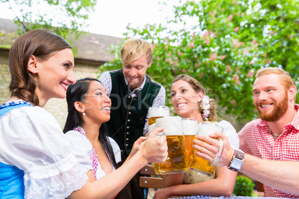 Friends clinking glasses in beer garden Stock photo © Kzenon