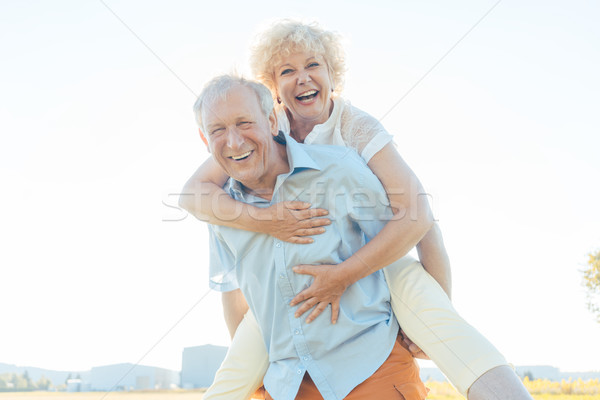 Happy senior man laughing while carrying his partner on his back Stock photo © Kzenon