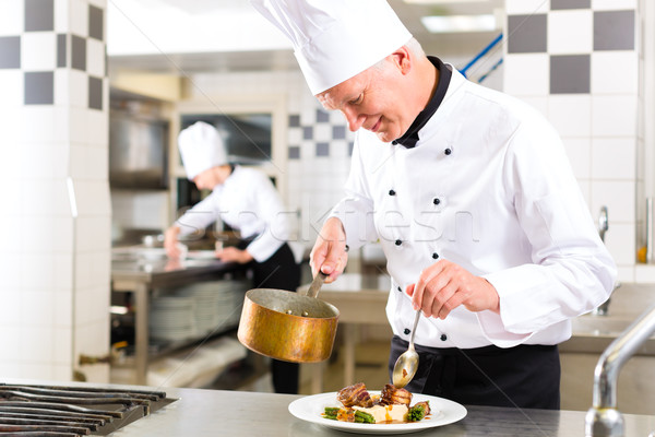 Chef in hotel or restaurant kitchen cooking Stock photo © Kzenon