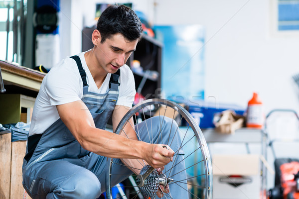 Man as bicycle mechanic working in workshop Stock photo © Kzenon