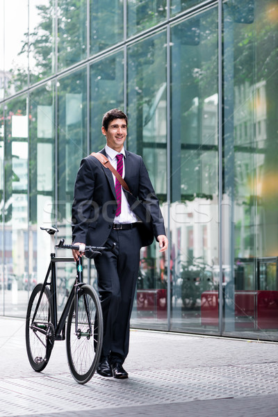 Stock photo: Businessman wheeling a bicycle through town