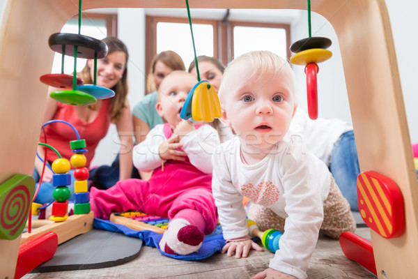Stock photo: Cute baby girl showing curiosity by trying to reach multicolored toys
