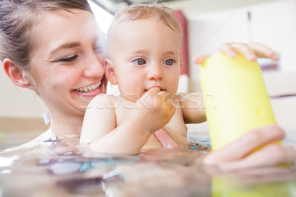 Baby in paddle pond reaching for toy ball in water Stock photo © Kzenon