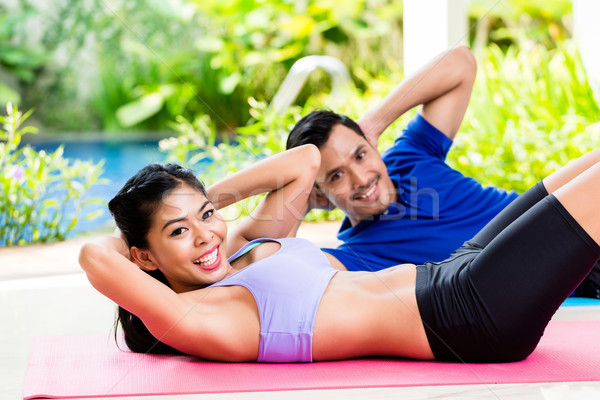 Asian fitness couple doing sit-up in tropical home Stock photo © Kzenon