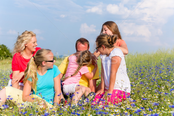 Family sitting on meadow in flowers Stock photo © Kzenon