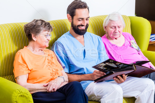 Geriatric nurse looking at pictures with seniors Stock photo © Kzenon