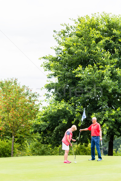 Senior woman and man playing golf putting on green Stock photo © Kzenon