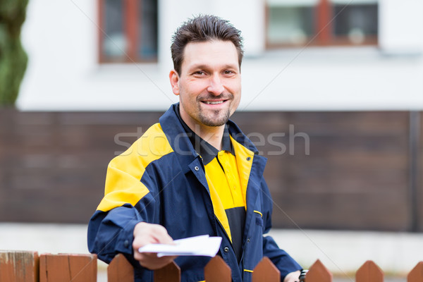 Mailman passing letters to addressee over fence Stock photo © Kzenon