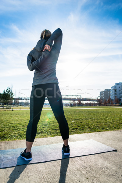 Rear view of a fit woman practicing a shoulder stretch for warmi Stock photo © Kzenon