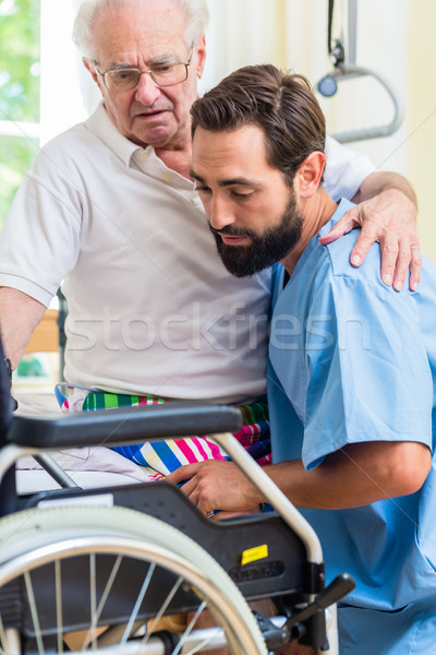 Elderly care nurse helping senior from bed to wheel chair  Stock photo © Kzenon