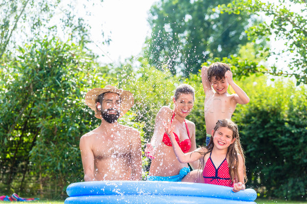 Family cooling down splashing water in garden pool  Stock photo © Kzenon