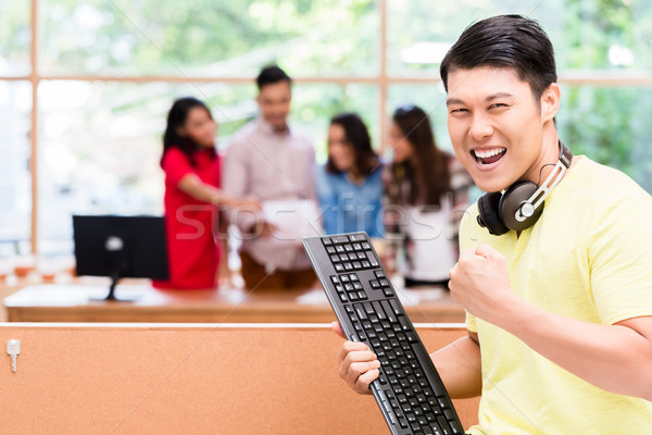 Young Chinese employee happy for his successful work on computer Stock photo © Kzenon