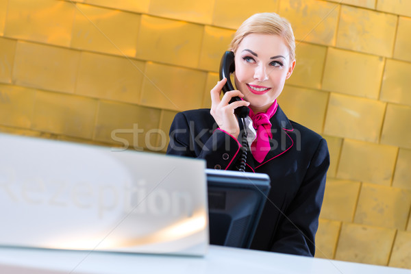 Hotel receptionist with phone on front desk Stock photo © Kzenon