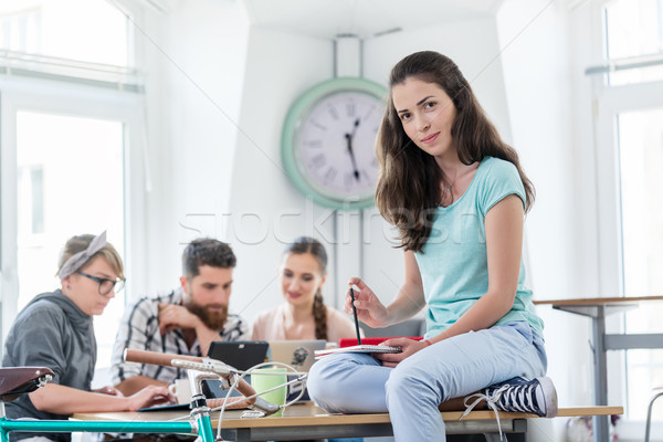 Beautiful young woman sitting on a desk during work in a modern  Stock photo © Kzenon