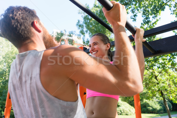 Fit young woman doing pull-ups supported by her strong partner Stock photo © Kzenon