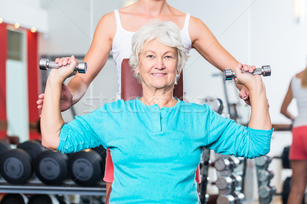 Idős nő edző tornaterem emel súlyzó Stock fotó © Kzenon