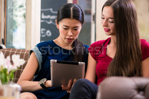 Two young friends searching for information on a tablet indoors Stock photo © Kzenon