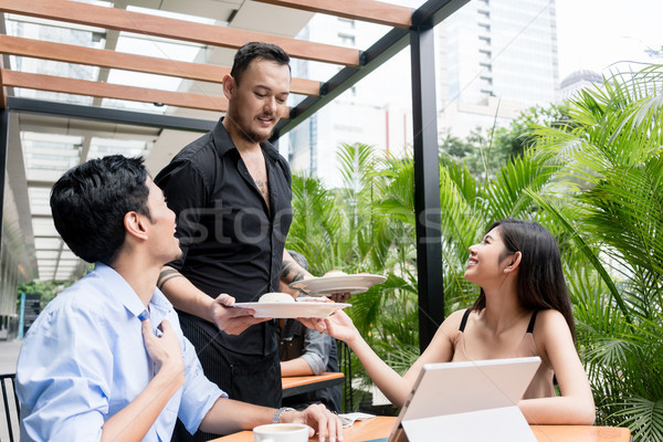 Cheerful waiter bringing two plates of food to the table Stock photo © Kzenon