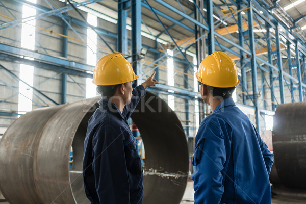 Skilled worker pointing up while giving instructions to an apprentice Stock photo © Kzenon