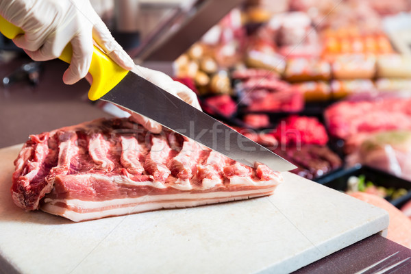 Butcher woman cutting piece of rib meat in her shop Stock photo © Kzenon