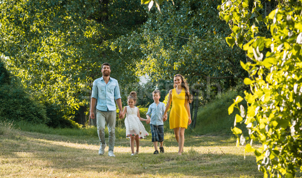 Happy family with two children holding hands during recreational walk Stock photo © Kzenon