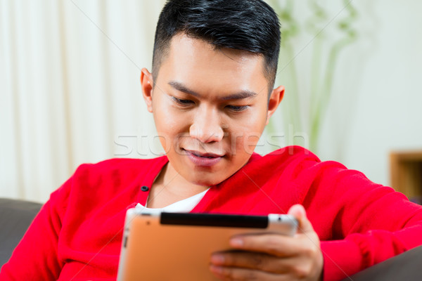 Stock photo: Young Asian man at home on the sofa