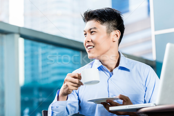 Stock photo: Chinese Businessman with coffee, laptop, and skyline