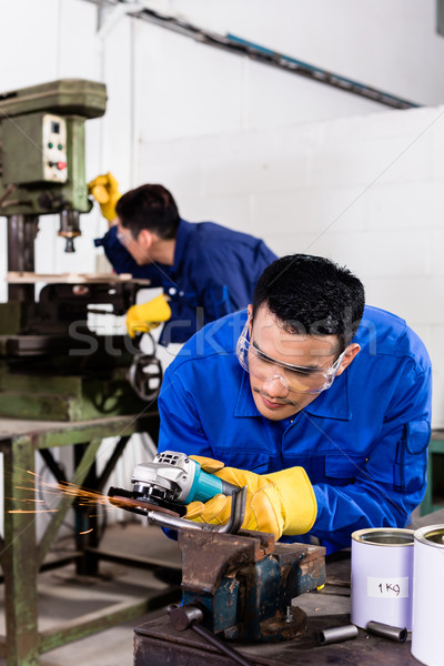 Metal workers in industrial workshop grinding Stock photo © Kzenon