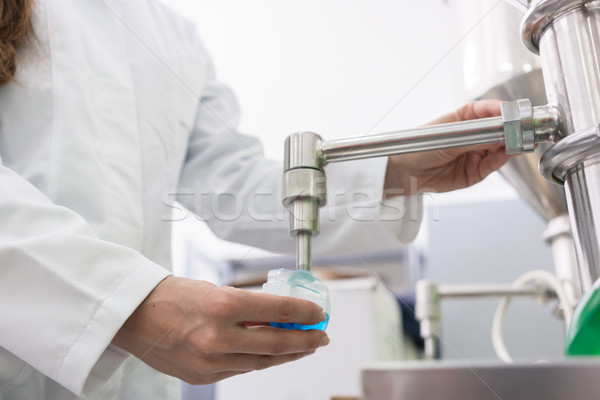 Technicien remplissage contenant liquide laboratoire vue de côté [[stock_photo]] © Kzenon