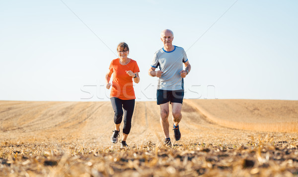Senior woman and man running or jogging on a field Stock photo © Kzenon